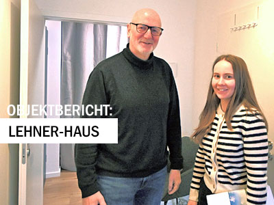 Zwei Personen stehen lächelnd in einem Büro oder Beratungsraum. Über dem Bild steht der Hinweis ‚Objektbericht: Lehner-Haus‘.